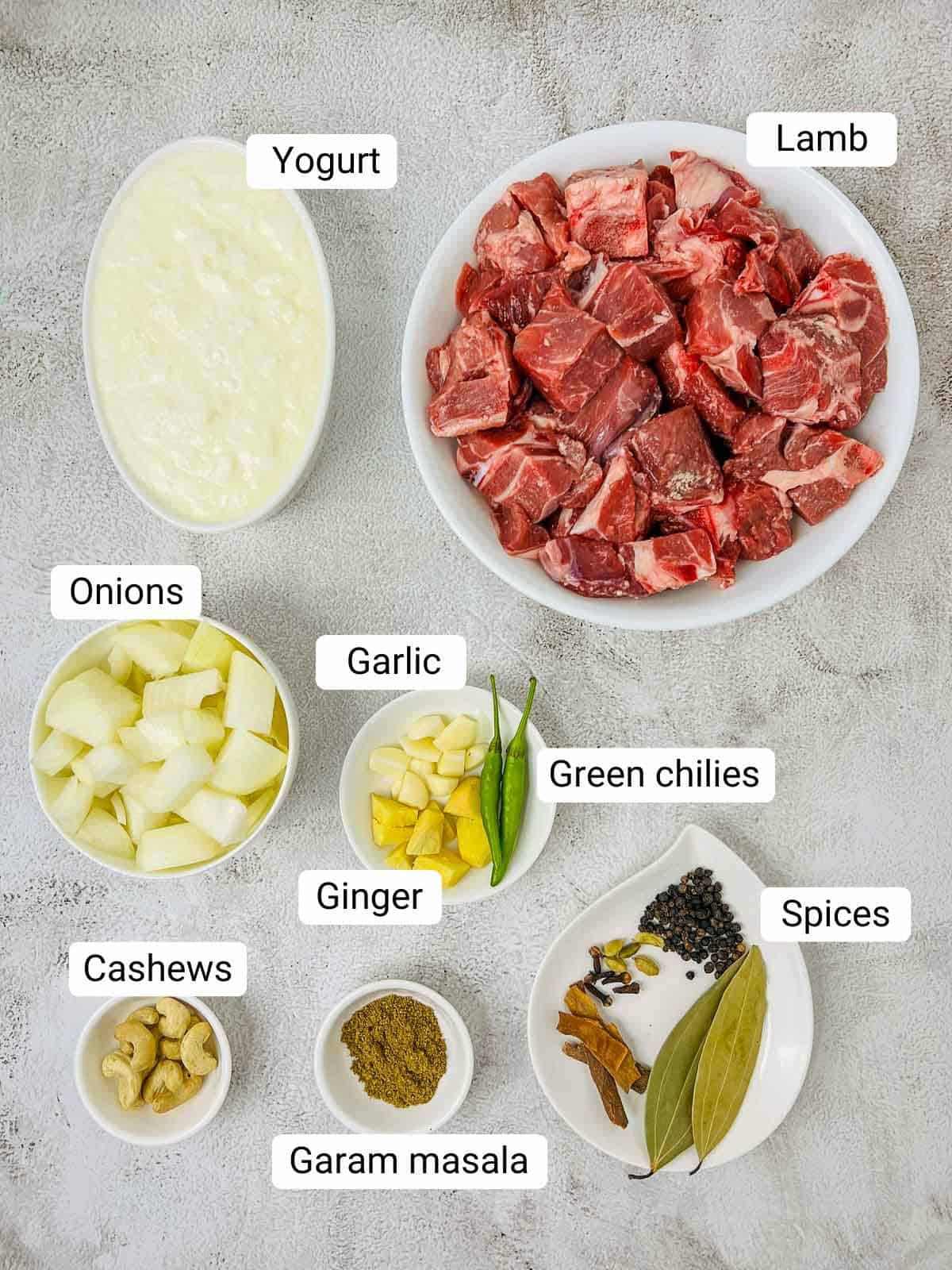 Ingredients to make lamb rezala placed on a white surface.