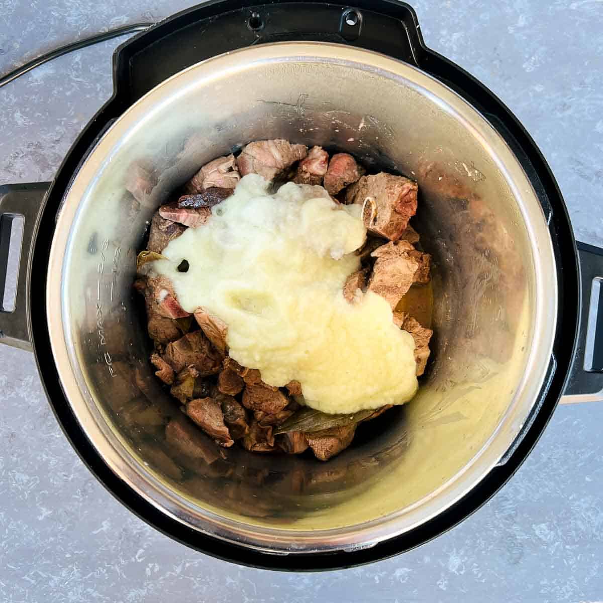 Onion paste added over the lamb in the Instant Pot.