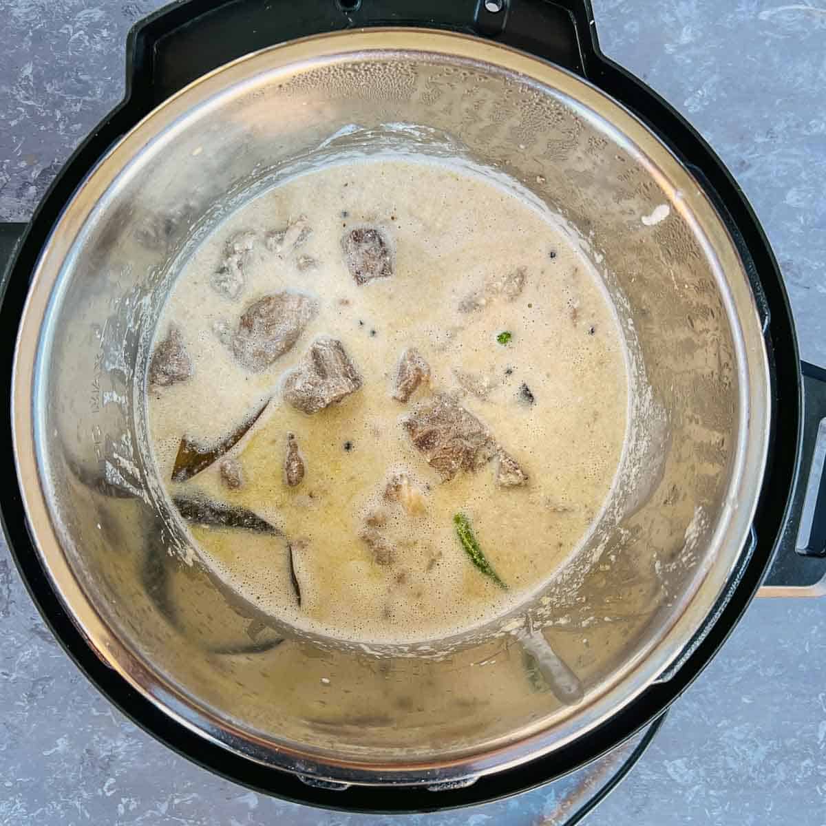 Whisked yogurt and cashew paste added to lamb-onion mixture in the Instant Pot.