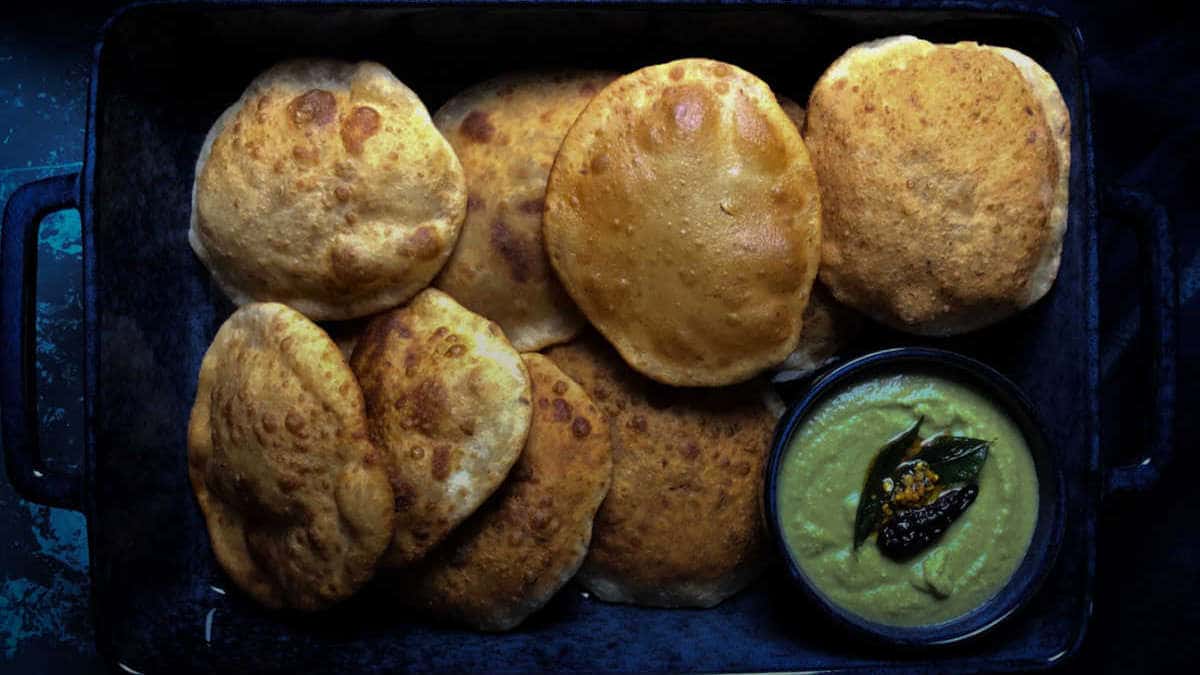 Mangalore buns placed in a wide tray with coconut chutney on the side.