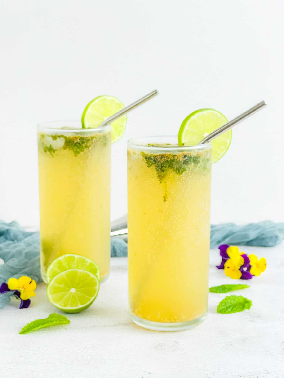 Masala mojito in two highball glasses with straw and lime ring.