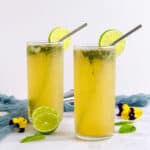 Masala mojito placed in two hiball glasses with straw and lime ring.