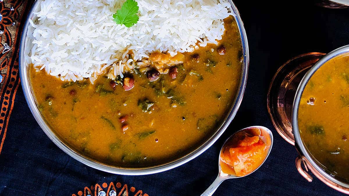 Palak sambar served with rice on a steel plate.