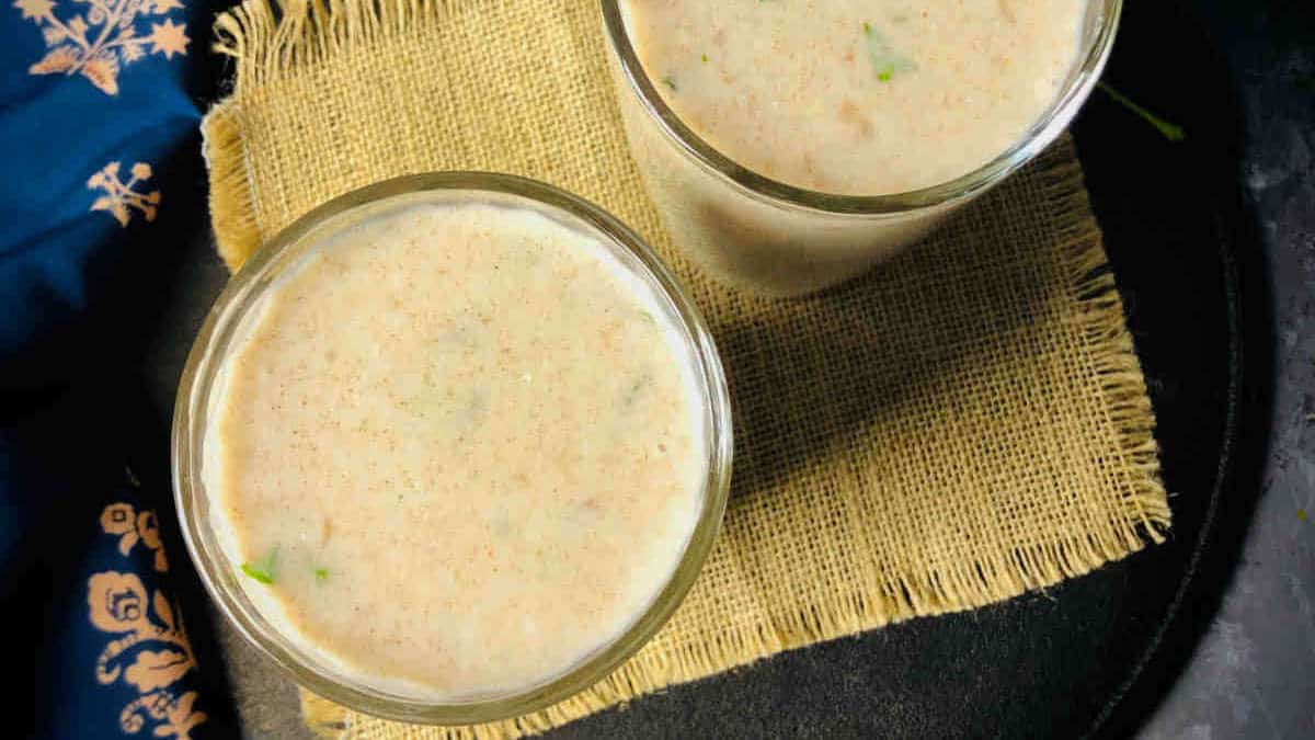 Two glasses of ragi ambali placed on a brown mat.