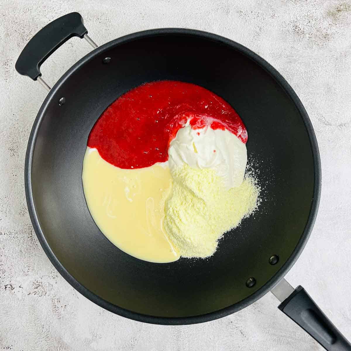 Raspberry puree, condensed milk, milk powder, and ricotta cheese placed in a non-stick pan.