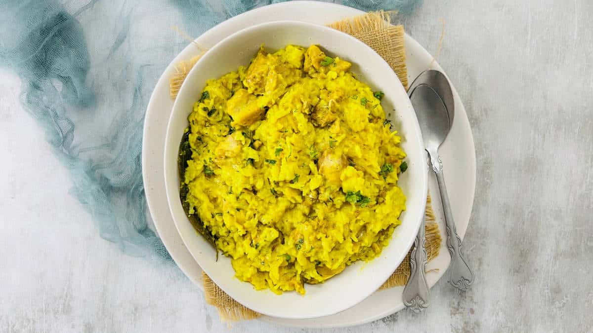Chicken khichdi in a white bowl with spoon in the background.