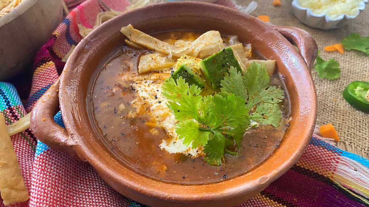 Chicken tortilla soup in a brown bowl.