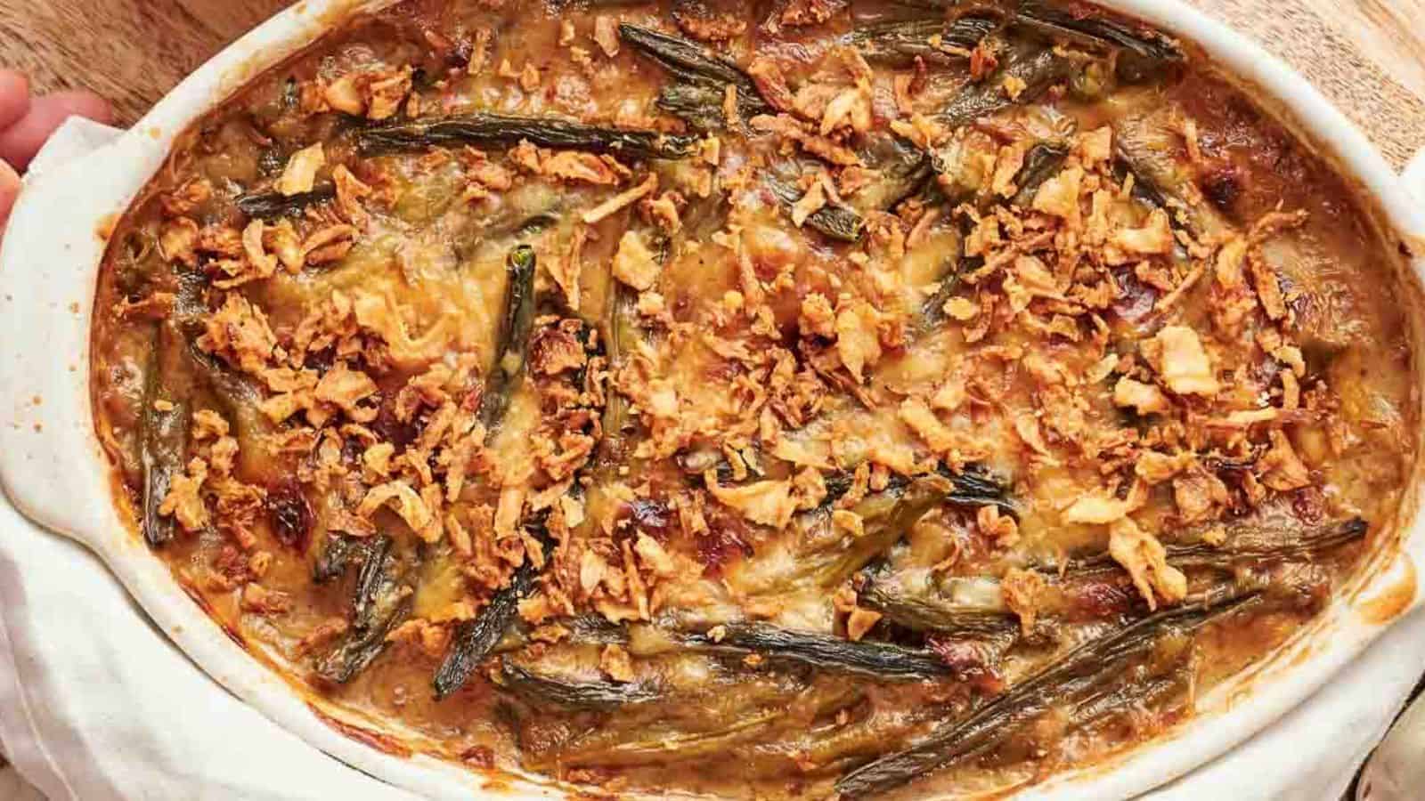 A casserole dish filled with green bean casserole with a spoon in it.