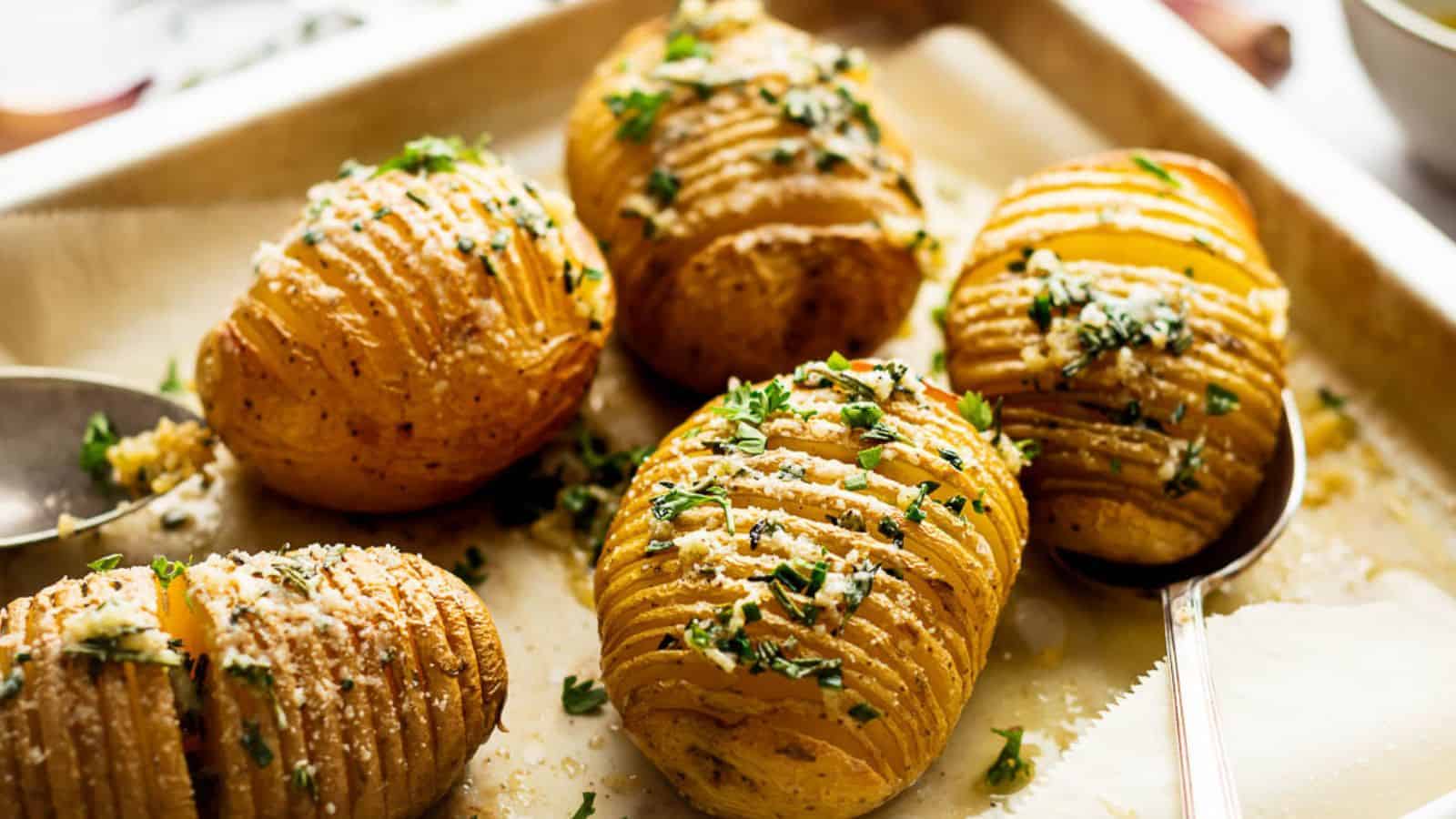 Roasted hasselback potatoes on a baking sheet with parmesan.