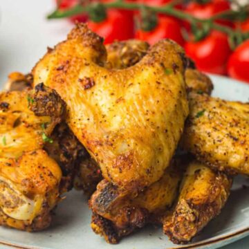 Air fryer chicken wings served with fresh tomatoes and herbs on a plate.