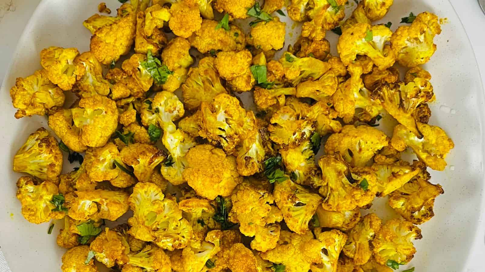 Air Fryer Cauliflower with turmeric and herbs served in a white dish.