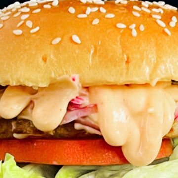 Juicy aloo tikki burger with creamy sauce, lettuce, and tomato.