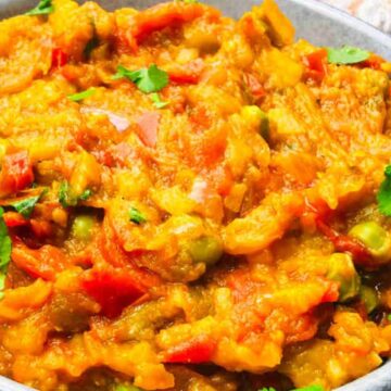 A bowl of cooked mixed vegetable curry garnished with fresh cilantro.