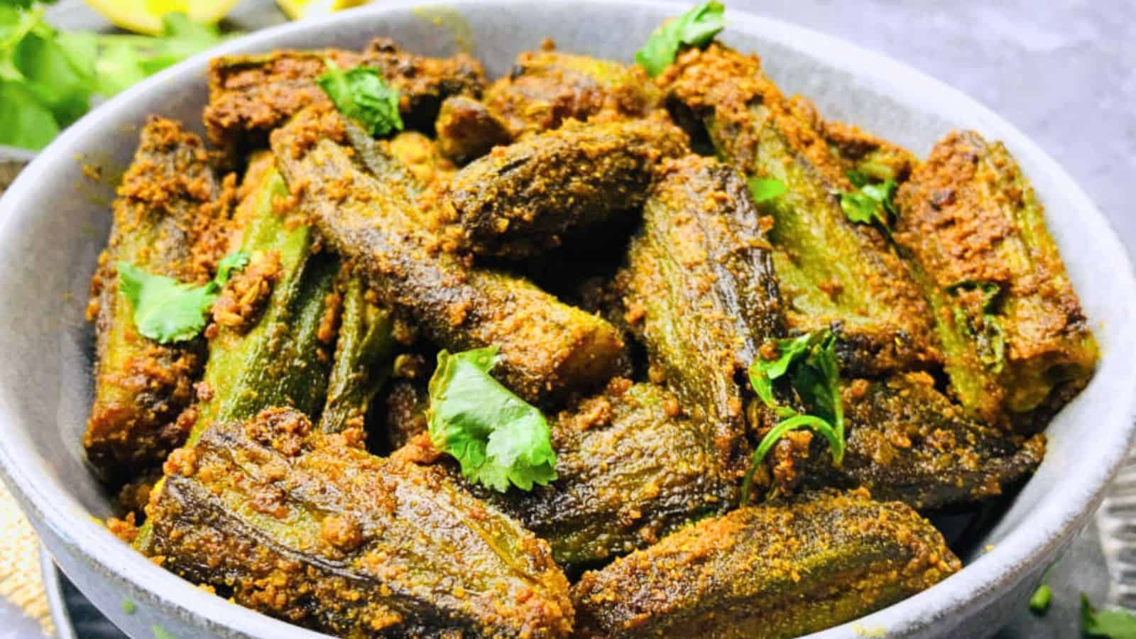 A bowl of Bharwa Bhindi garnished with fresh cilantro, served on a textured tablecloth.