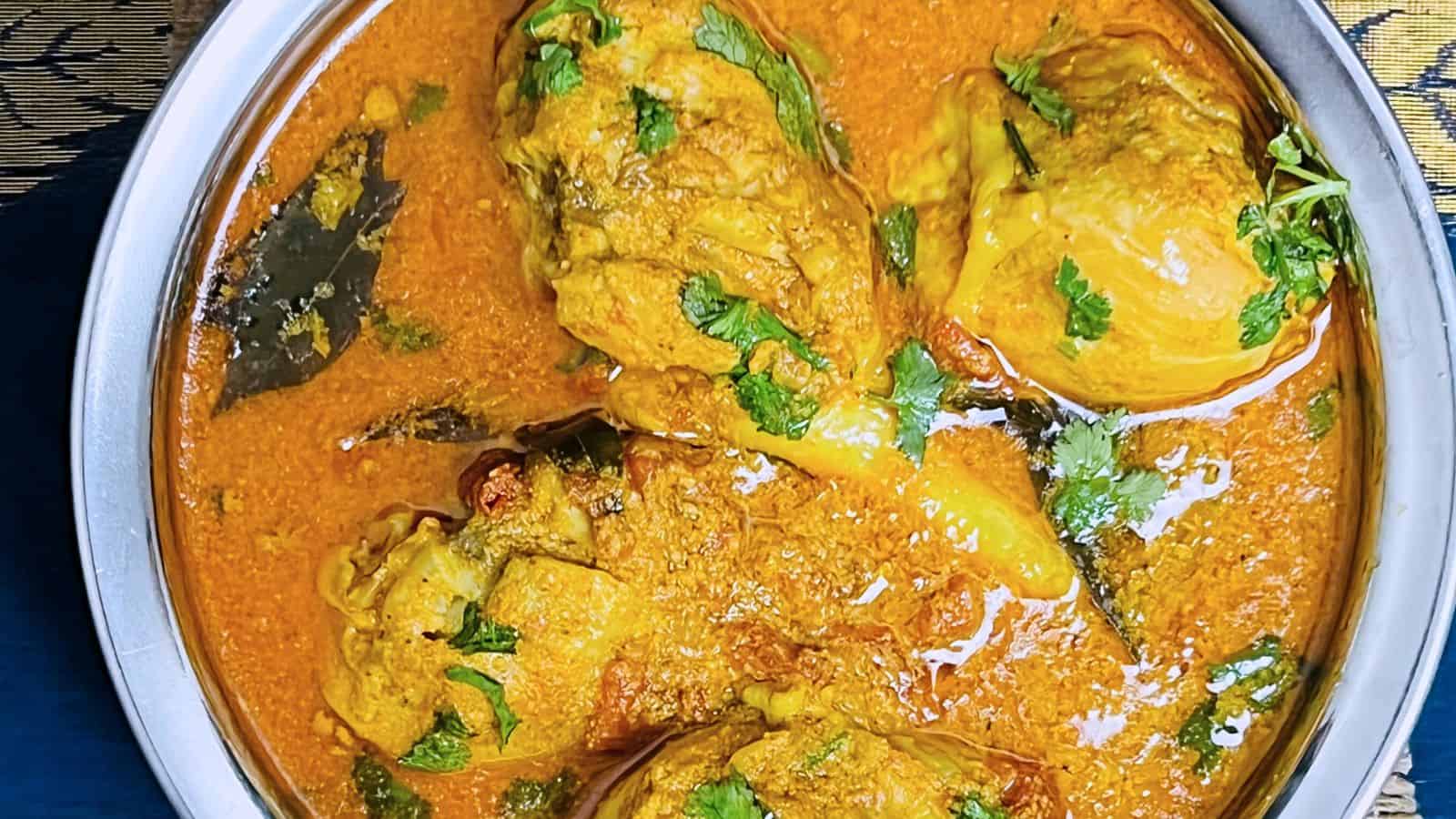 A bowl of Chettinad Chicken Curry garnished with fresh cilantro, displaying chunks of chicken and spices in a rich, creamy sauce.