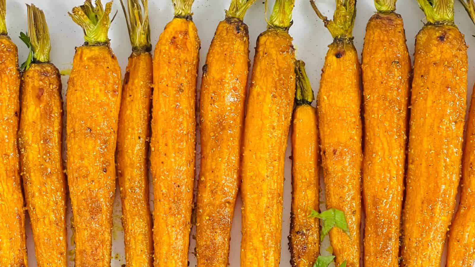Curried Roasted Carrots with seasoning, lined up neatly on a white surface.