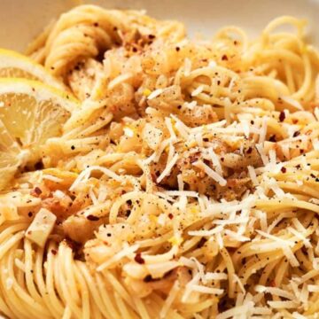 A bowl of pasta with lemon slices and parmesan cheese.