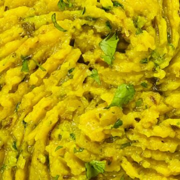 Close-up of Masala Mashed Potatoes garnished with herbs.