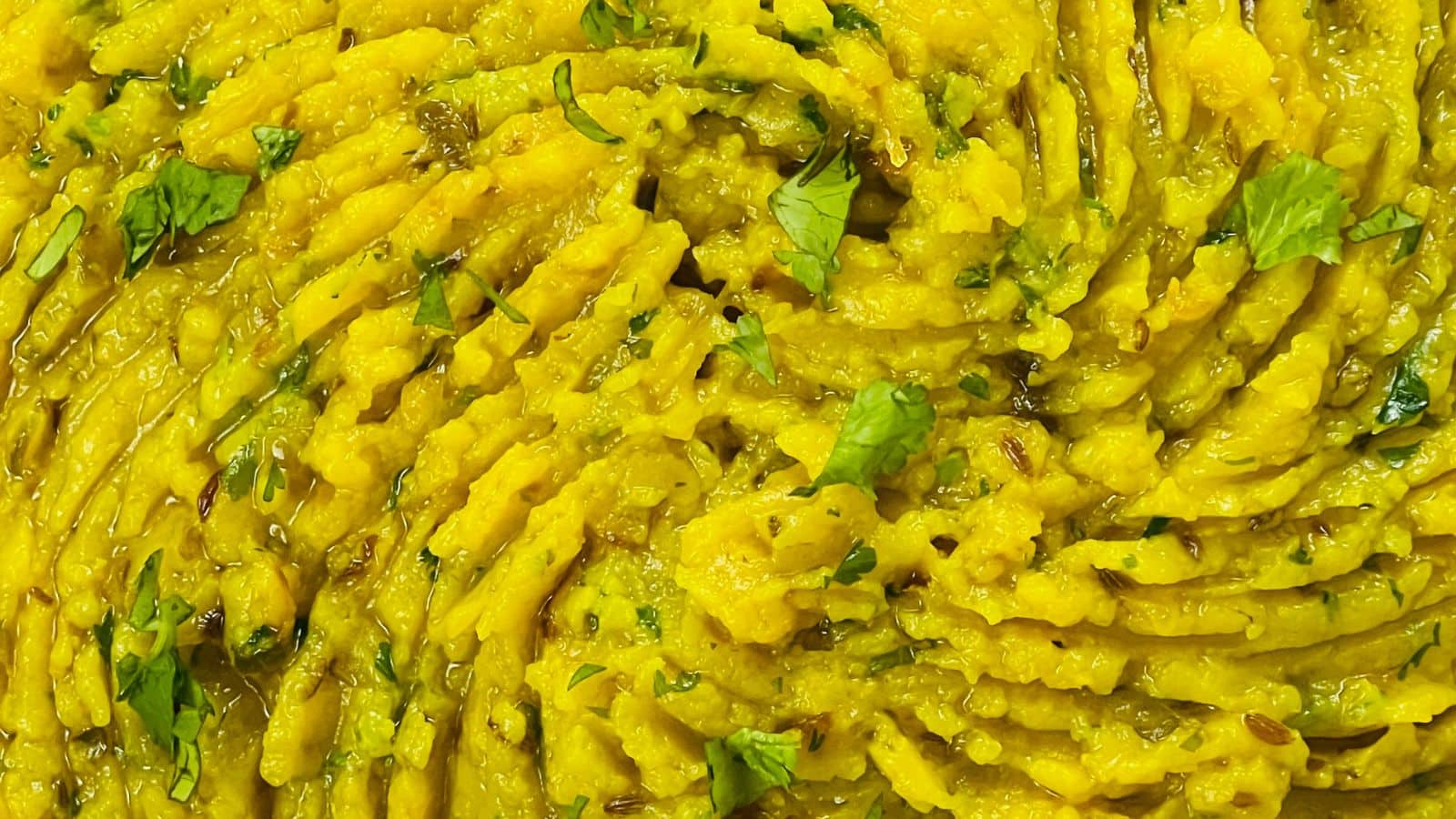 Close-up of Masala Mashed Potatoes garnished with herbs.
