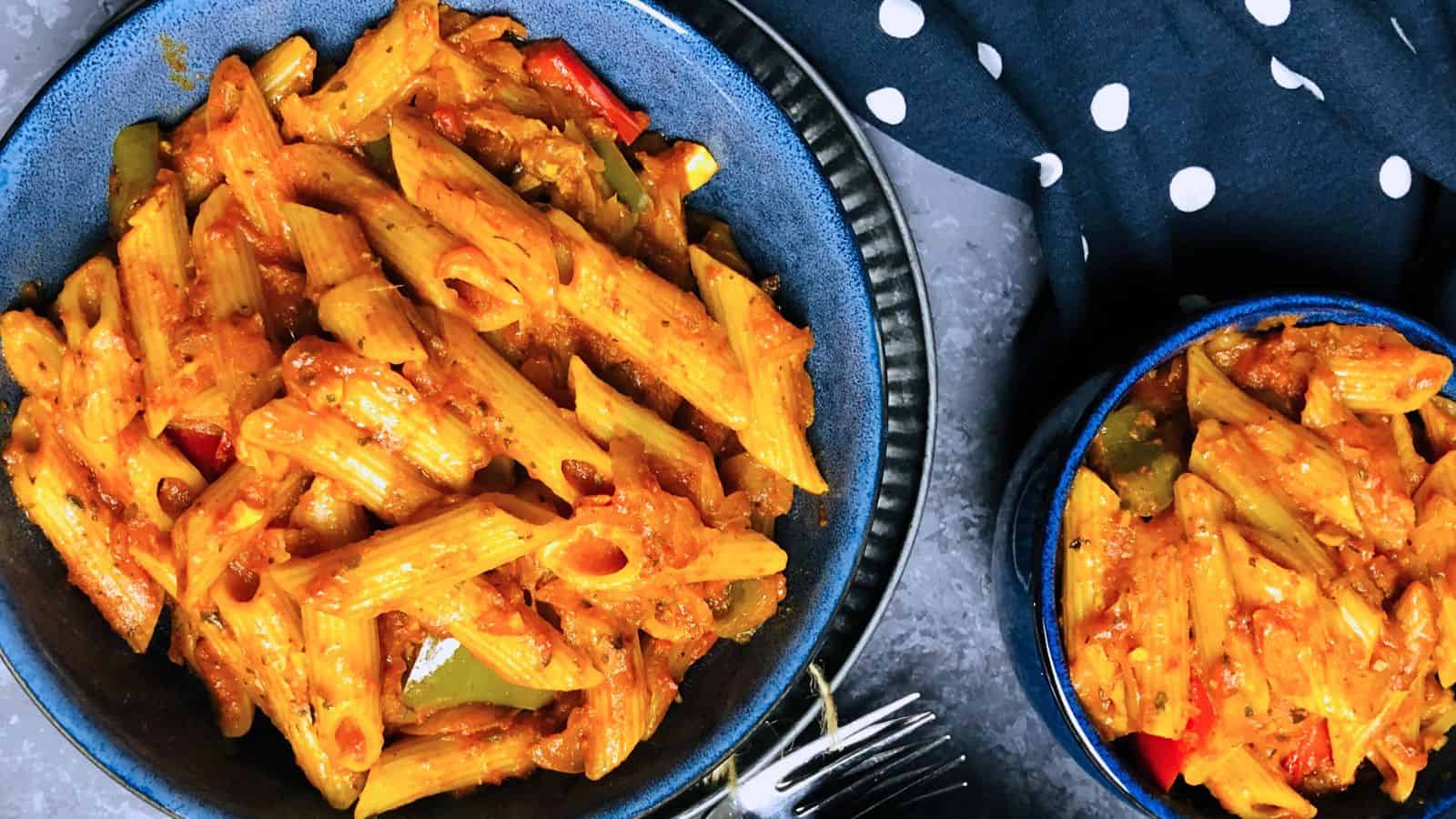 Two bowls of Masala Pasta, served on a dark blue textured surface.