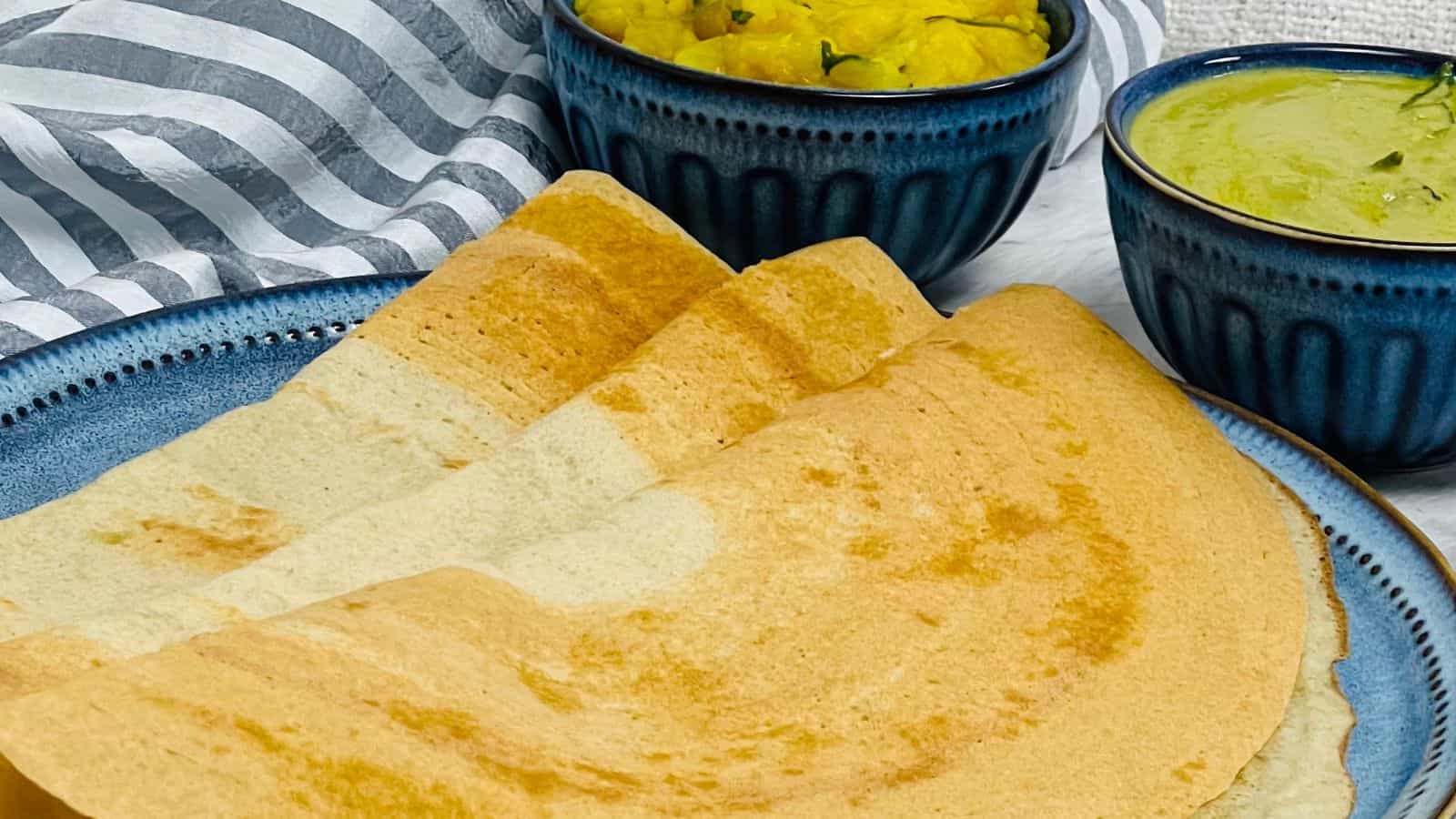 Freshly Quinoa dosa served with accompaniments in blue bowls.