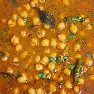 A top view of a bowl of South Indian Chana Masala with cilantro and green chilies.