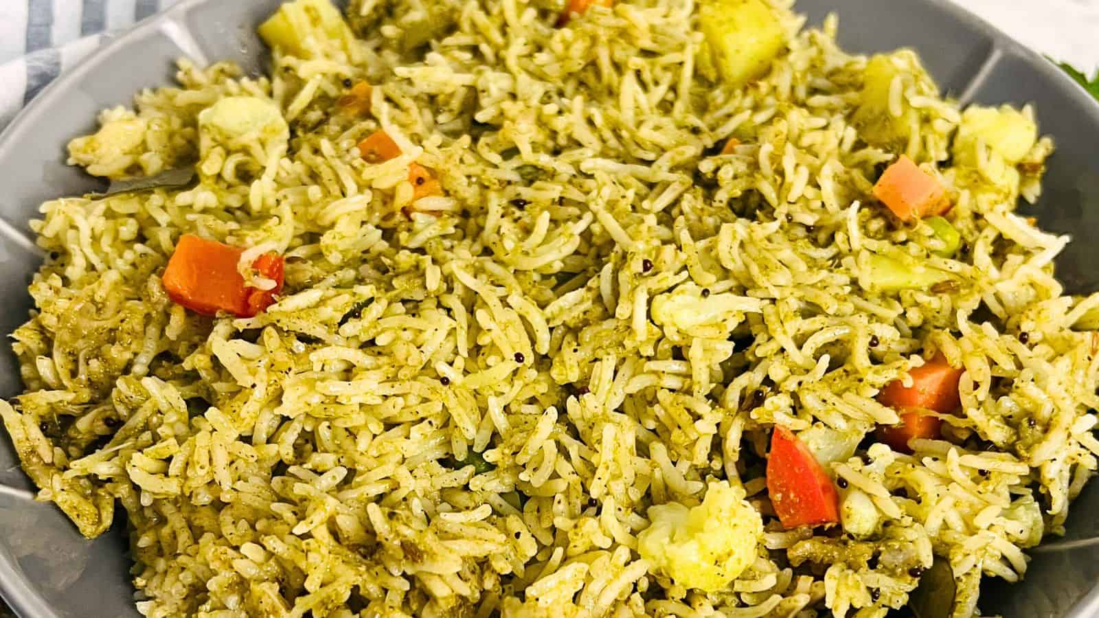 A close-up of a bowl of Vegetable Pulao containing rice mixed with chunks of carrots and cauliflower.