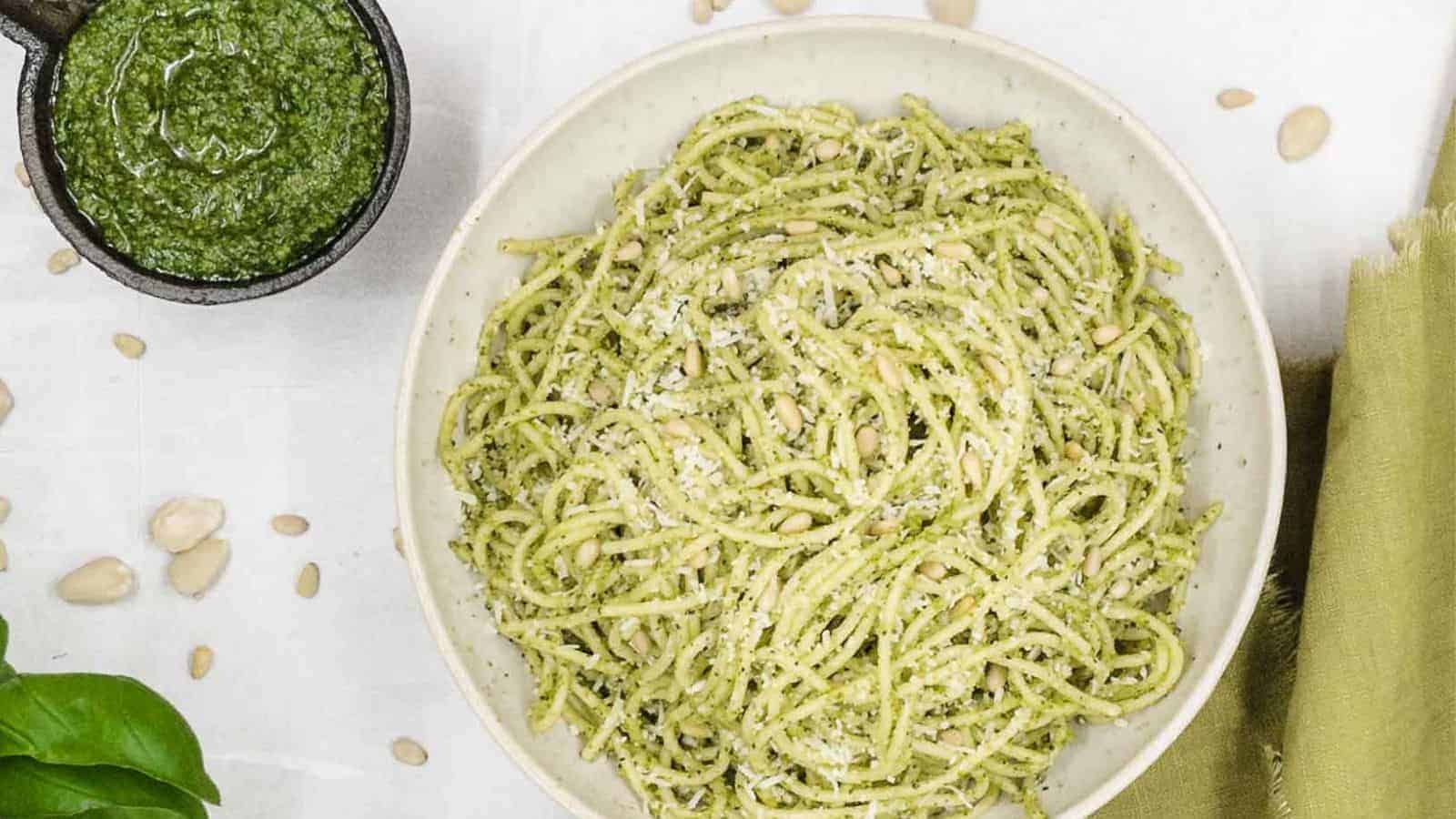 A bowl of pesto pasta with pine nuts and parmesan cheese.