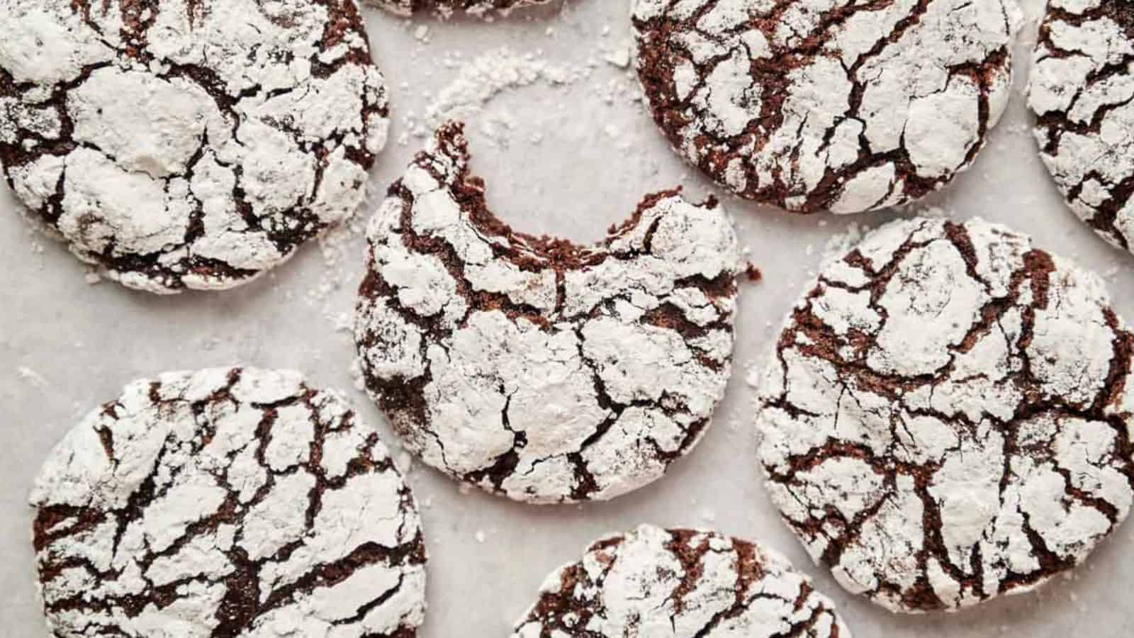 Chocolate crinkle cookies dusted with powdered sugar on a parchment paper.