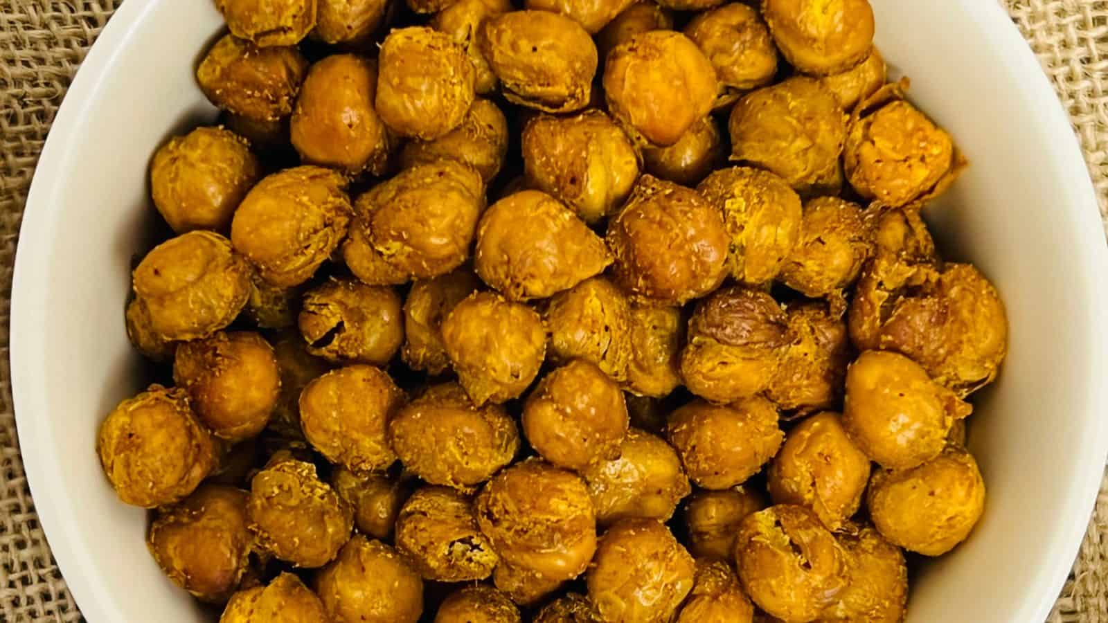 A bowl of roasted chickpeas with seasoning, viewed from above.