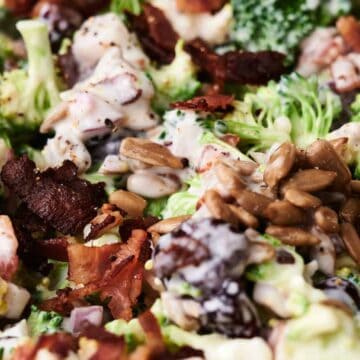 Close-up of a delightful broccoli salad with crispy bacon, sunflower seeds, and a creamy dressing. Mixed ingredients are visible in detail, showcasing the vibrant textures and colors of this fresh broccoli salad.