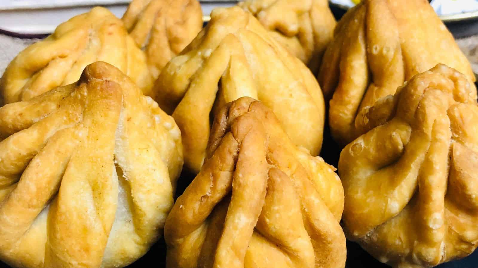 A close-up view of several freshly made fried dumplings, with a golden-brown crust, arranged in a group.