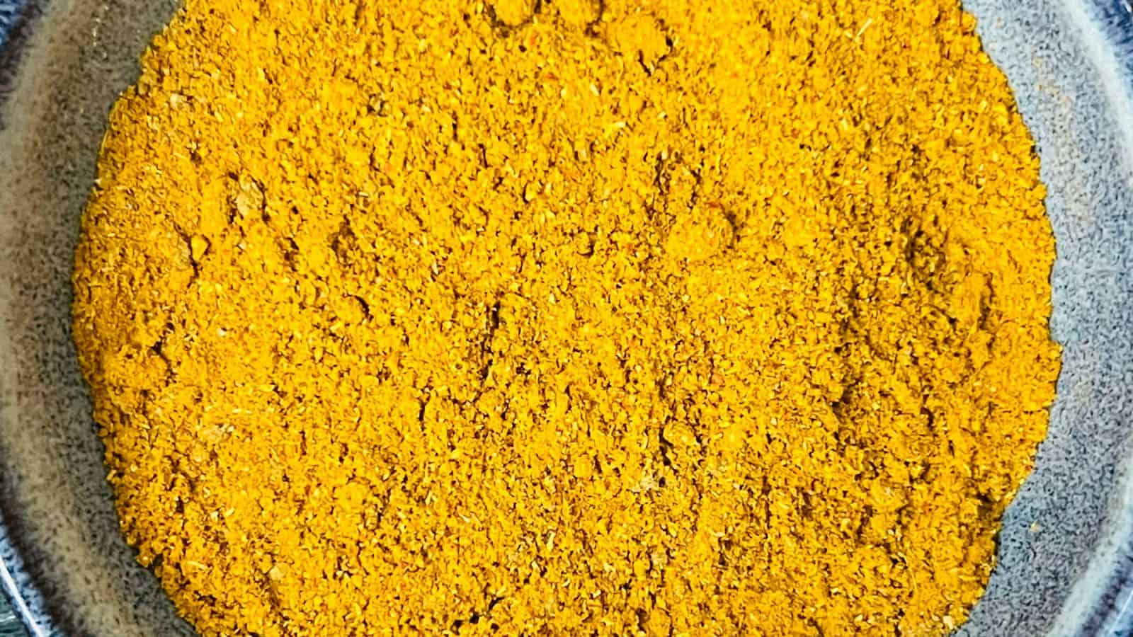 A close-up of a circular plate filled with a bright yellow-orange powdered spice.