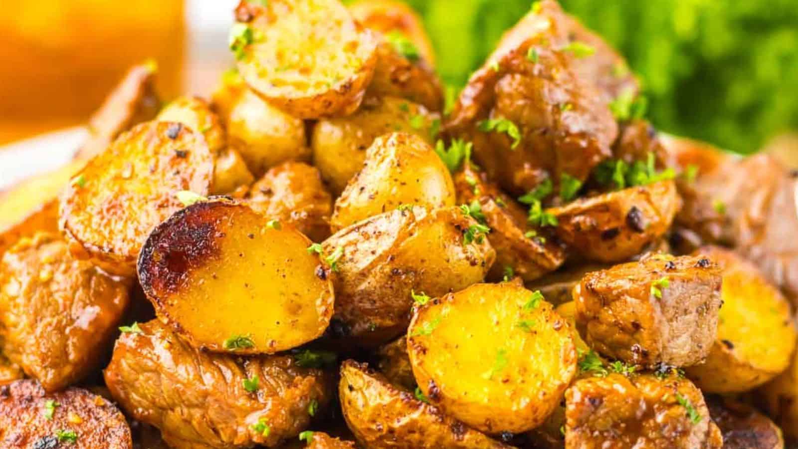 A close-up image of honey chipotle seasoned roasted potatoes garnished with parsley, served alongside grilled steak and lettuce.