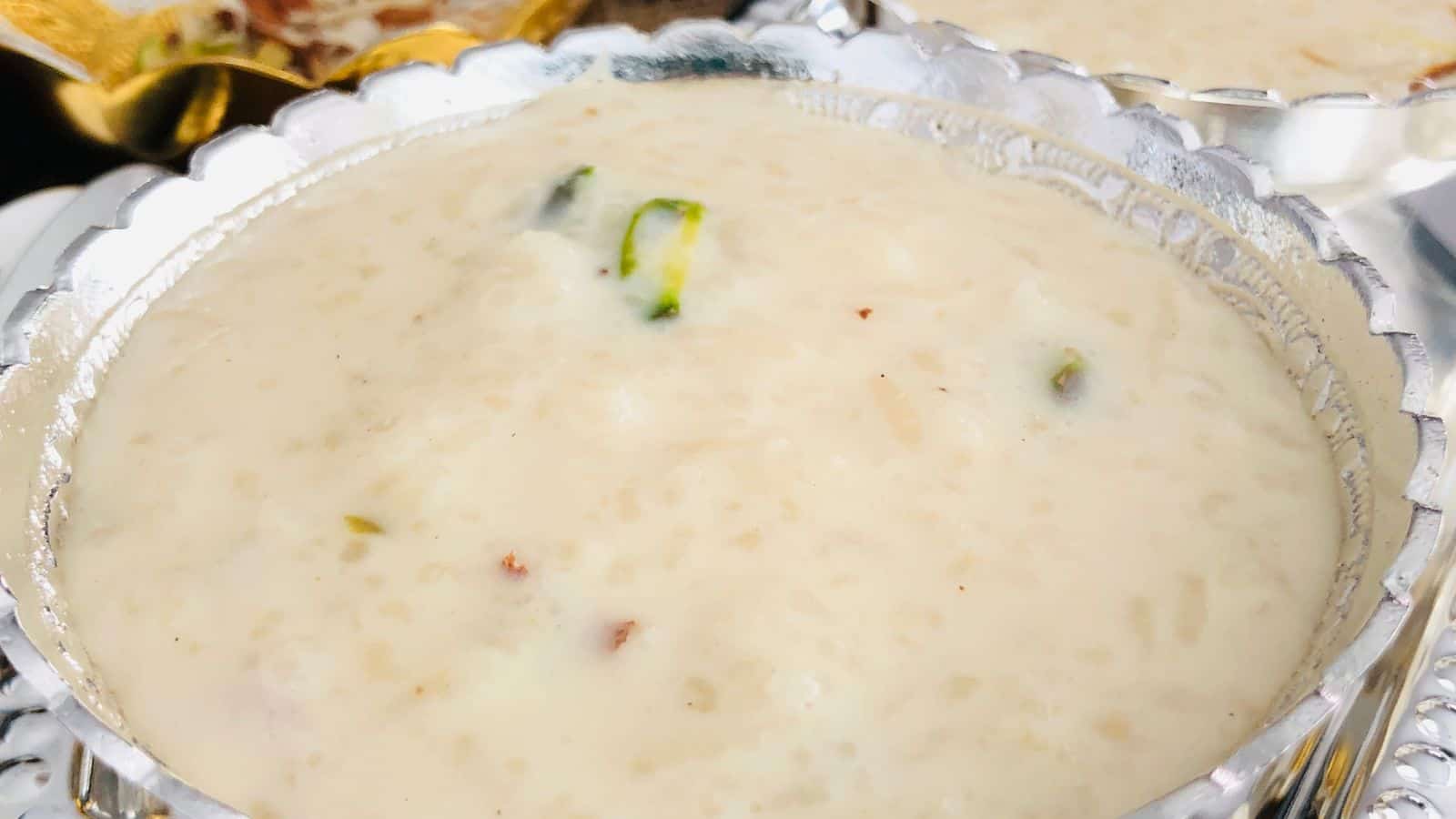 Close-up of kheer, an indian rice pudding, in a silver bowl garnished with pistachios and served as a dessert.