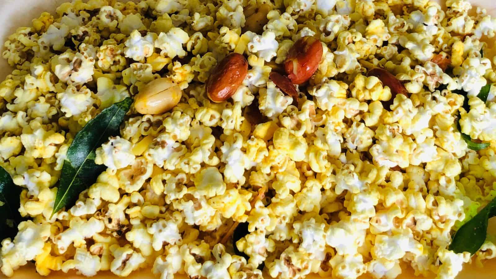 A bowl of spiced popcorn mixed with nuts and curry leaves.