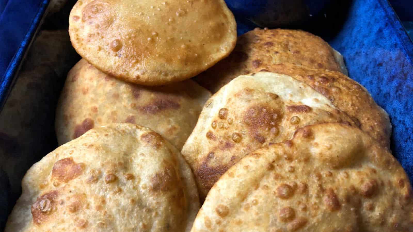 Close-up of a basket containing several pieces of puffy, golden-brown fried bread.