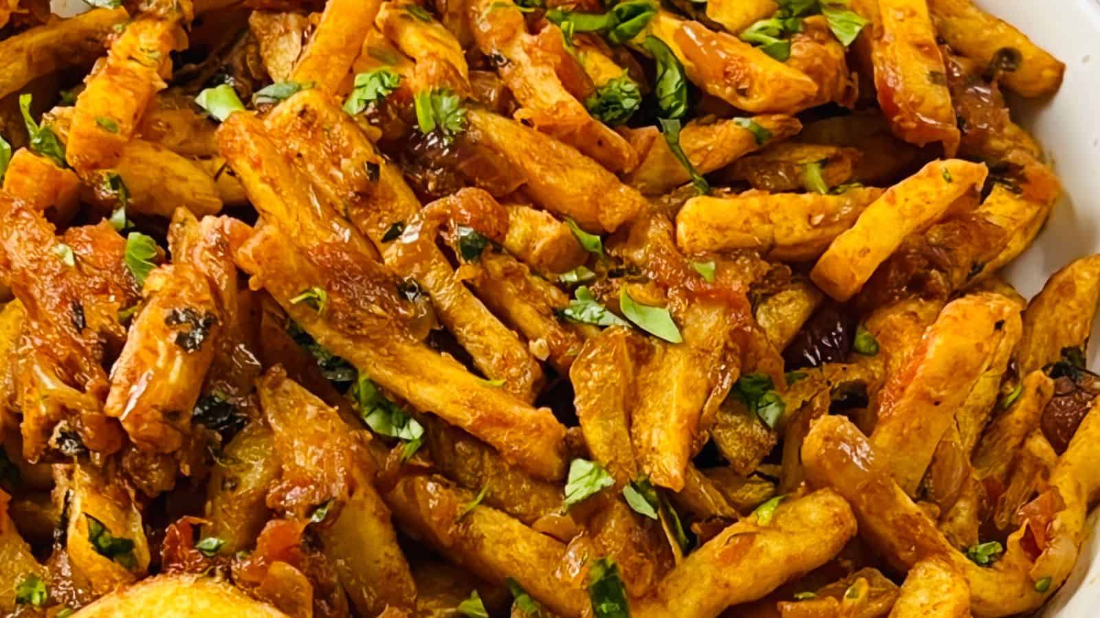 Close-up of a dish filled with golden brown fries, garnished with chopped fresh herbs.