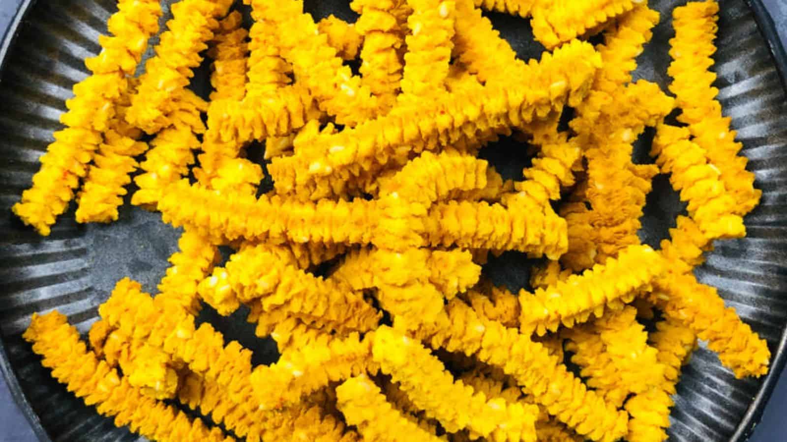 A plate filled with bright yellow, crinkle-cut fries arranged in a pile.