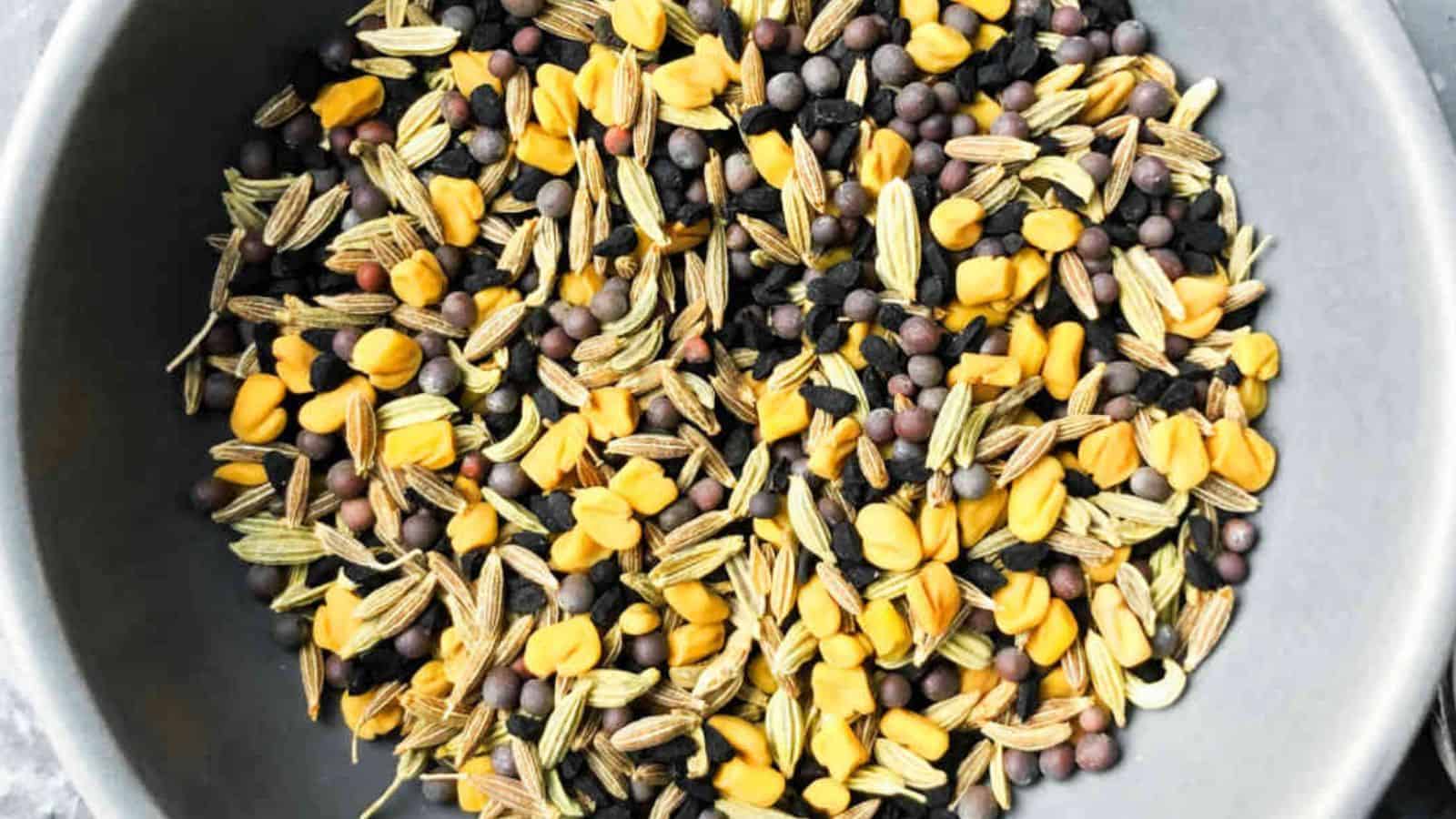 A bowl containing a mix of black lentils, yellow split peas, and various grains and seeds.