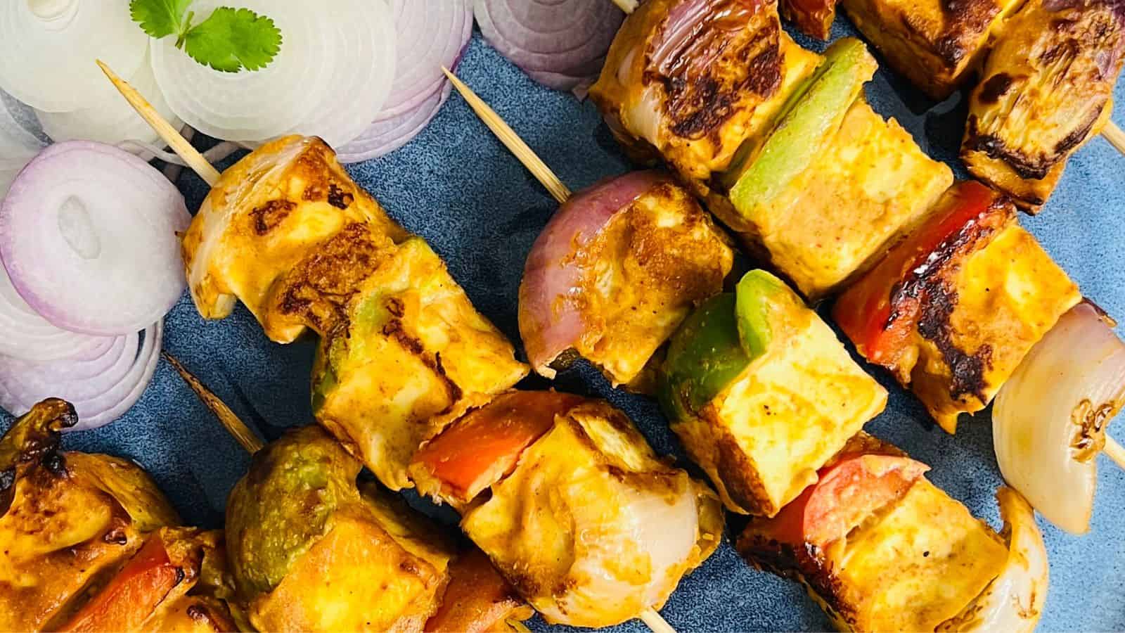 A vibrant dish of Paneer tikka masala garnished with cilantro in a blue bowl, served alongside naan bread.