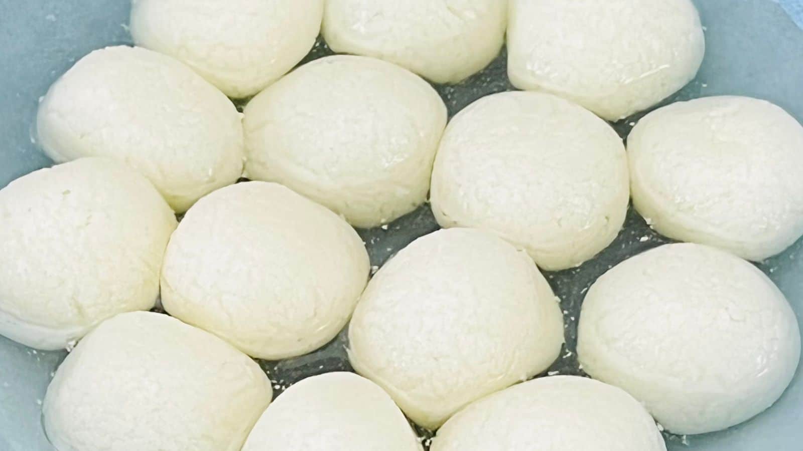 A bowl filled with round, white dough balls close together, likely for baking or cooking.