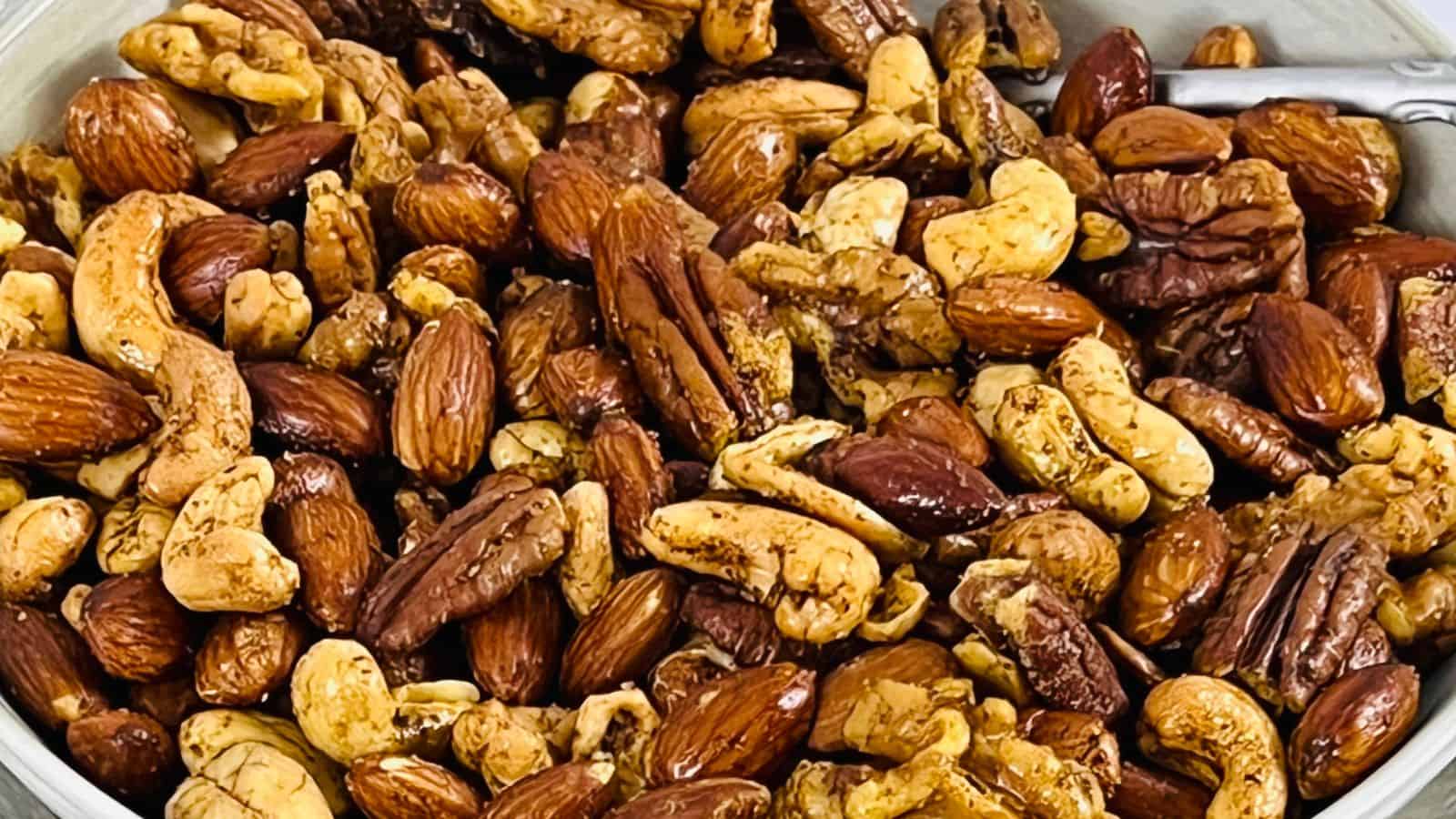 A close-up image of a bowl filled with mixed nuts, including almonds, pecans, cashews, and walnuts.