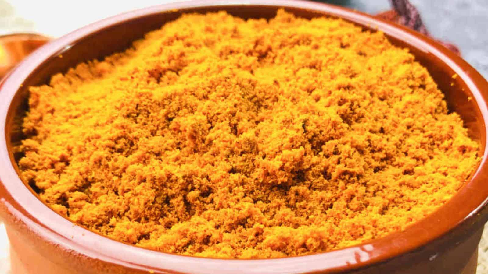 A bowl filled with bright orange turmeric powder.