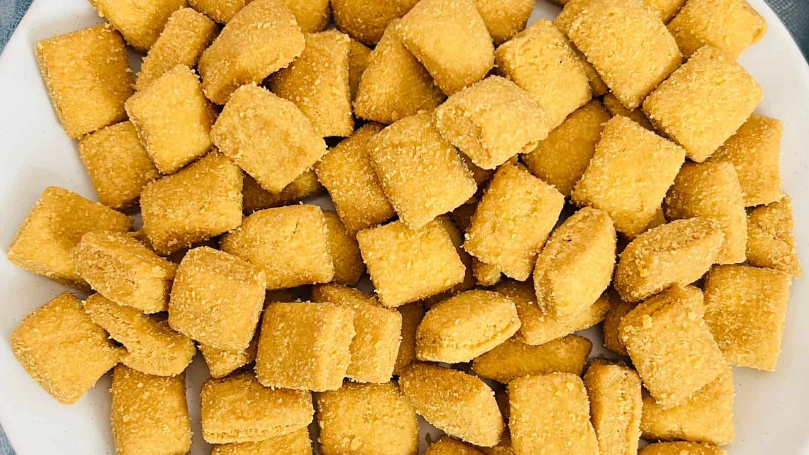 A plate filled with many small, square, breaded food items.