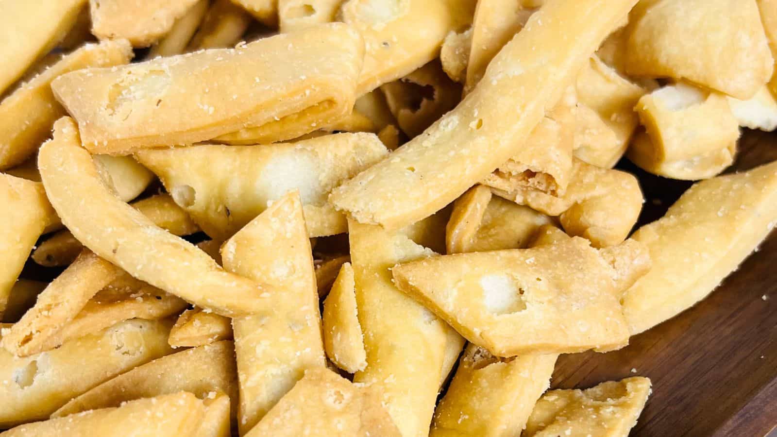 Close-up of a pile of crispy, golden-brown fried dough pieces on a wooden surface.