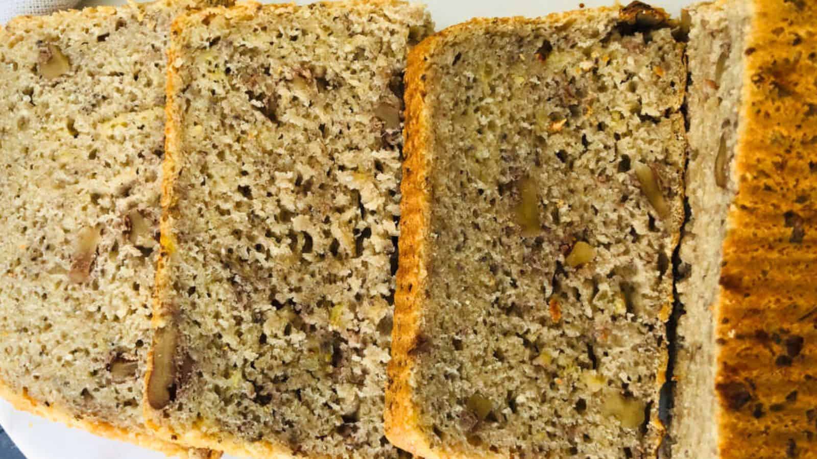 Four slices of nut bread are arranged side by side, showing a dense texture with visible pieces of nuts throughout.