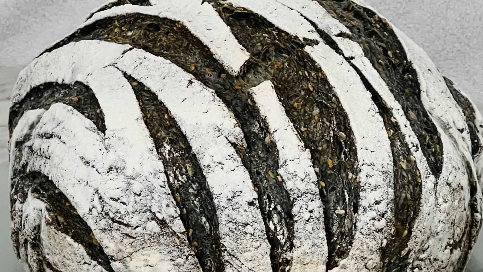 A close-up of a round loaf of bread with a dark crust and white flour stripes, giving a zebra-like pattern.
