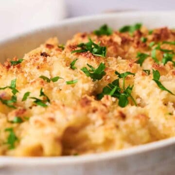 A baking dish filled with golden-brown baked tuna noodle casserole, topped with breadcrumbs and garnished with chopped parsley.