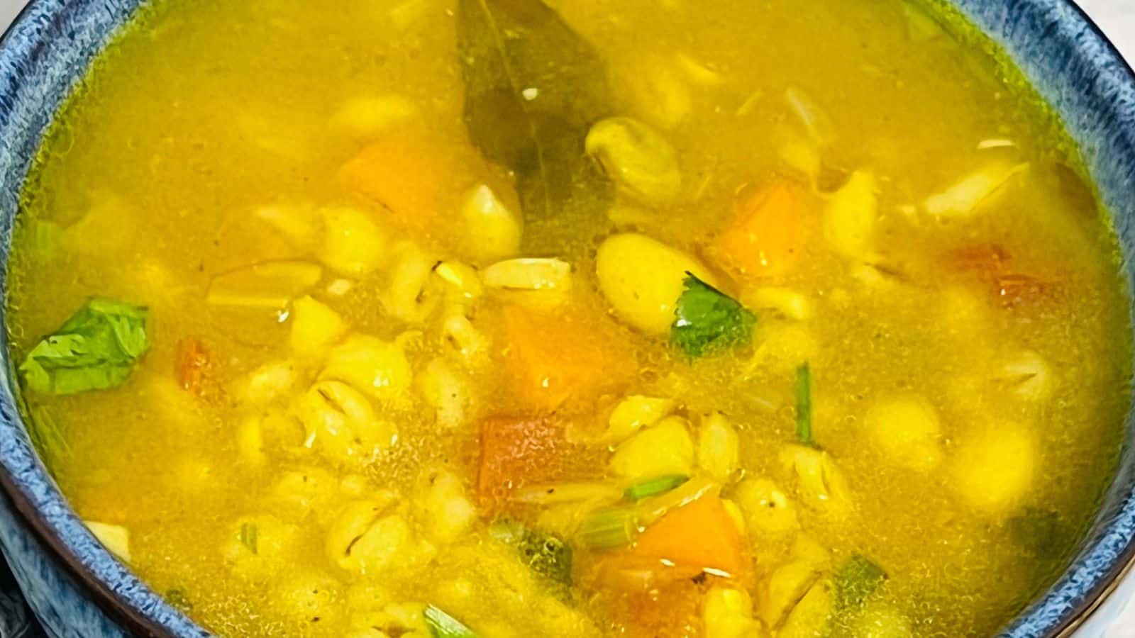 Vegetable barley soup bowls on a marble surface.